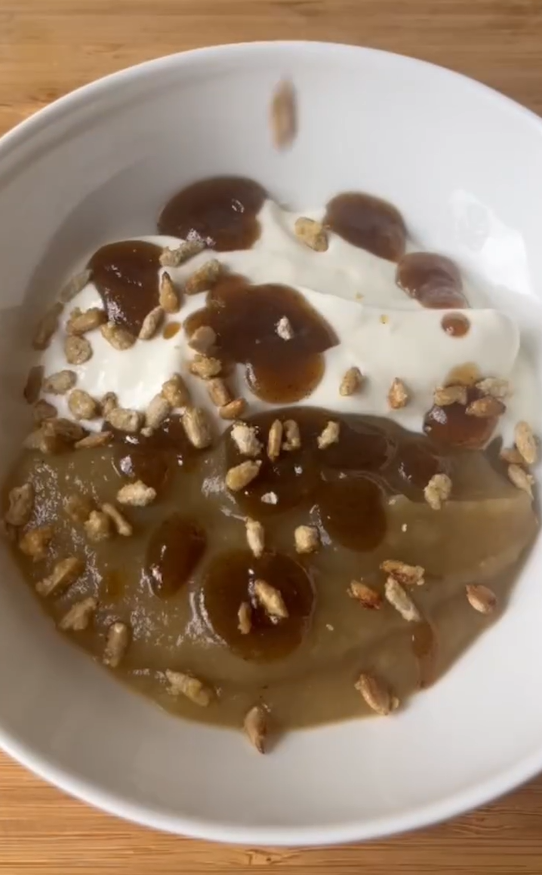Verrine de compote de pommes nappée d'un coulis brun épicé, parsemée de graines de tournesol caramélisées
