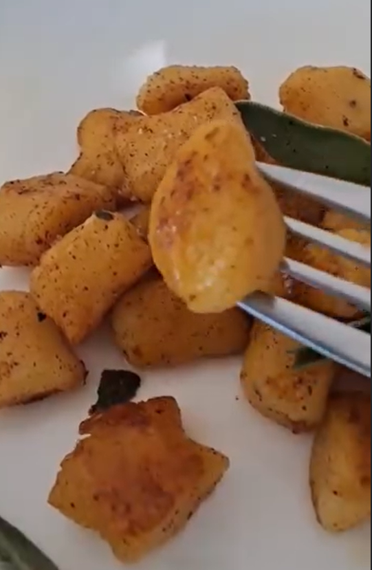 Plat ovale rempli de gnocchis maison dorés au parmesan, photographiés en lumière naturelle