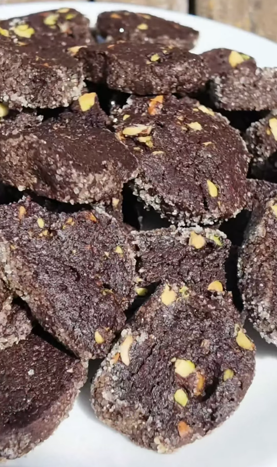 Assiette généreuse de sablés au chocolat parsemés de pistaches concassées, croûte sucrée et mie foncée et fondante