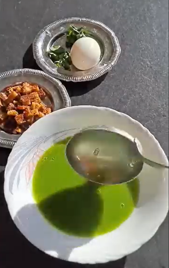 Bol de soupe de cresson verte, surmonté d'un œuf mollet, de croûtons dorés et de pousses de cresson cru